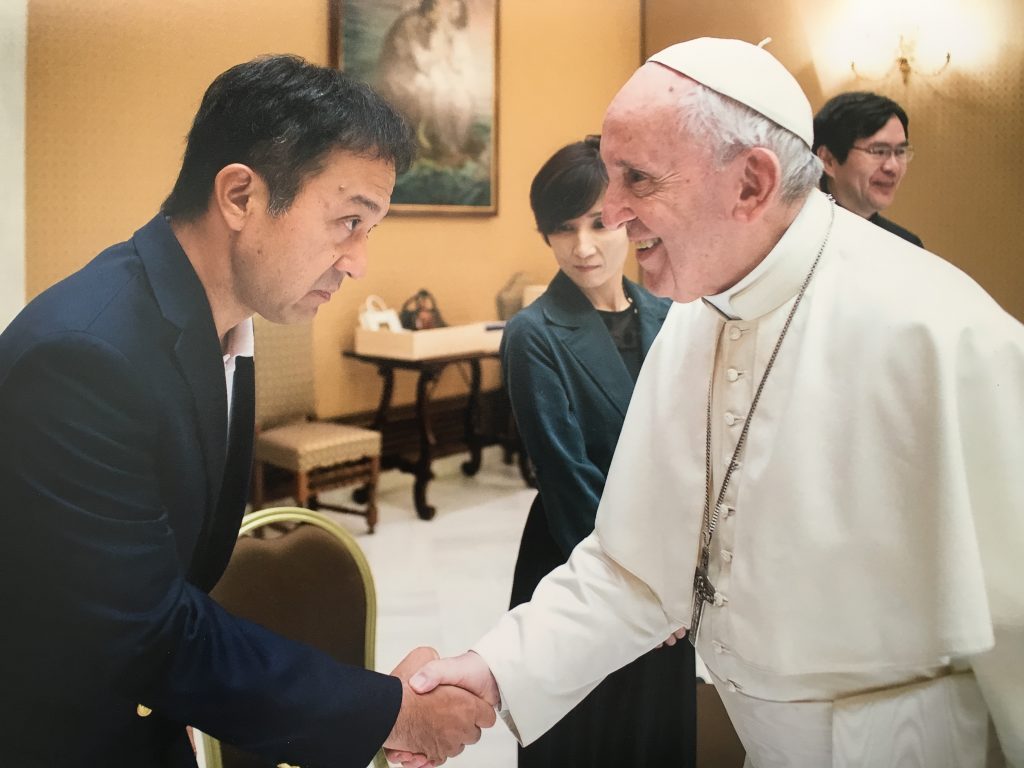 ローマ教皇と握手しているところ。